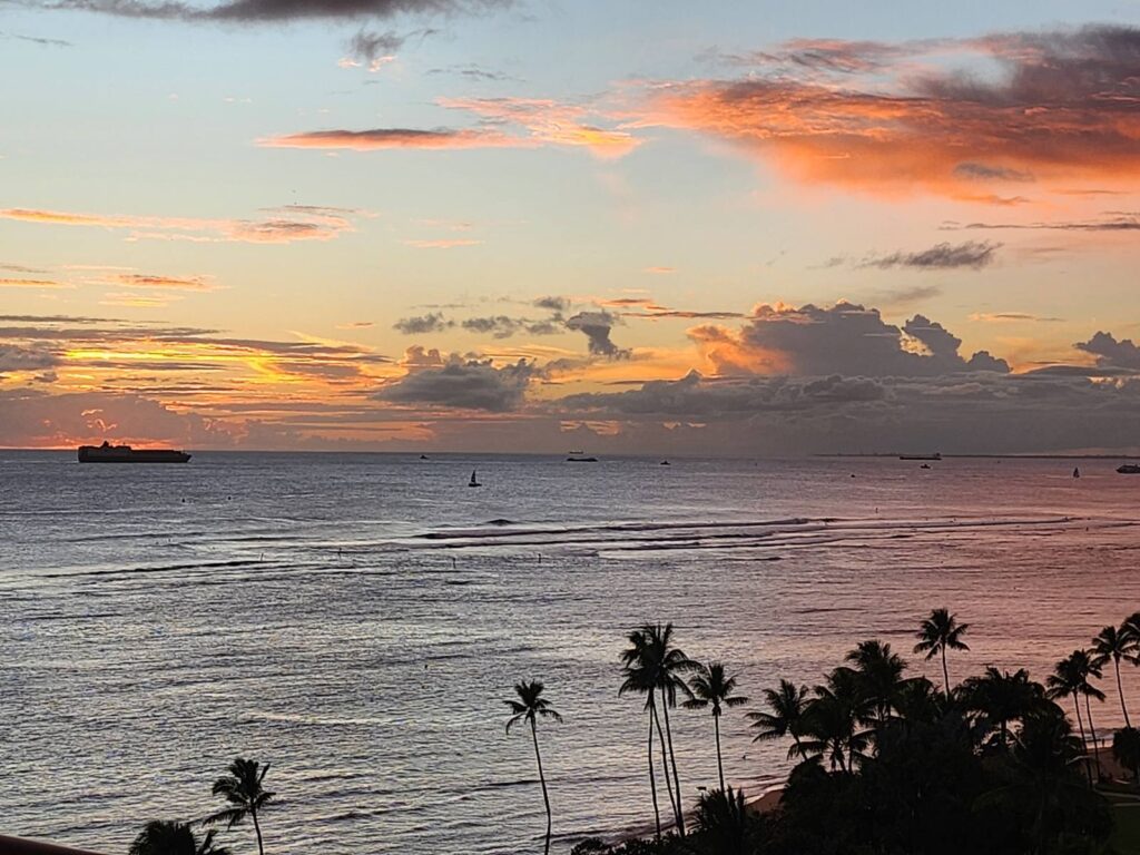 A picturesque sunset illuminates the ocean, featuring a lone ship gracefully navigating the tranquil waters.