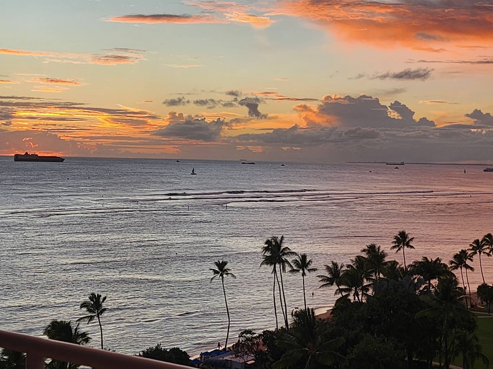The ocean at sunset, showcasing a ship against a backdrop of colorful skies and gentle waves.